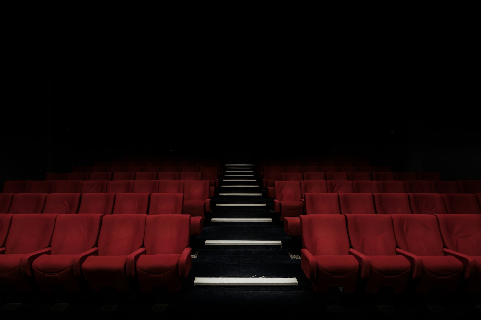 Salle de cinéma dans la pénombre, fauteuils rouges